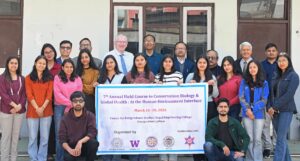 Nepal field course group photo. People standing holding a flag announcing the 7th annual field course.